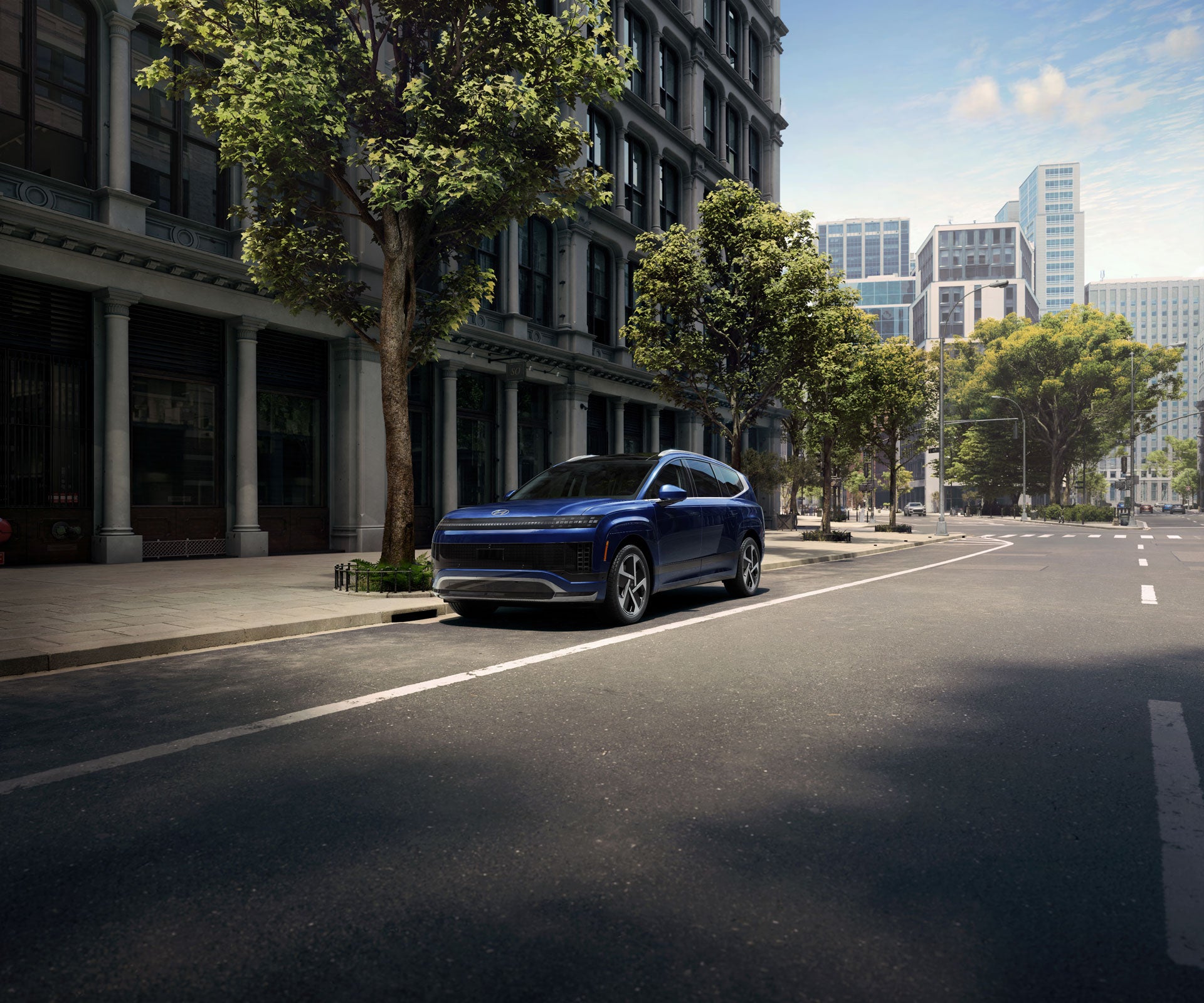 A blue SUV parked on a city street in front of a tall, old brick building, with trees lining the sidewalk.