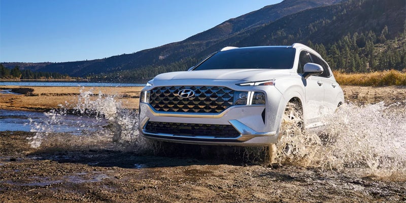 Hyundai Santa Fe SUV driving through water in an outdoor adventure setting.
