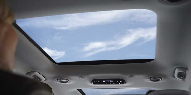 A sunroof showcases a bright, cloudy sky from inside a car's interior